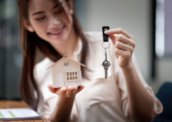 General Liability concept with a young Asian woman holding a key and little house in her hand.