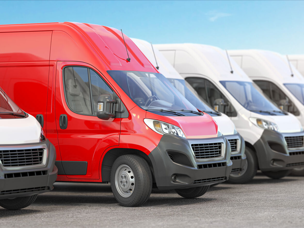Red business van parked in a line with other white business vans.