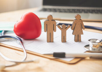 Group Health Insurance concept with stethoscope, red heart and stick family on a clip board.
