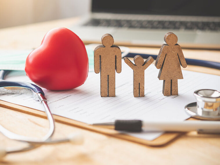 Group Health Insurance concept with stethoscope, red heart and stick family on a clip board.